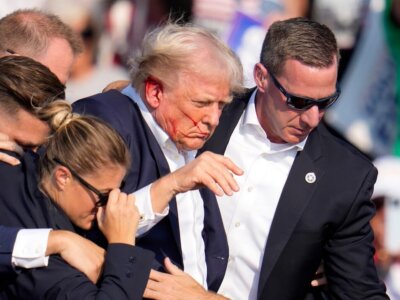 Republican presidential candidate former President Donald Trump is helped off the stage at a campaign event in Butler, Pa., on Saturday, July 13, 2024. (AP Photo/Gene J. Puskar)